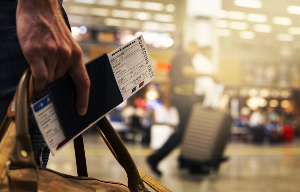 Traveler holding a passport and boarding pass inside a busy airport terminal, representing international travel and passport-related issues. Lost Passport Replacement in the USA